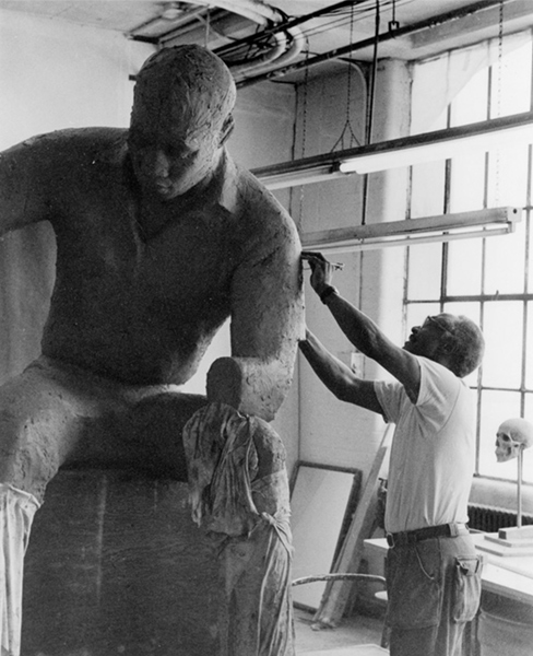 Artist John Wilson sculpts his 'Father and Son Reading' statue out of clay.