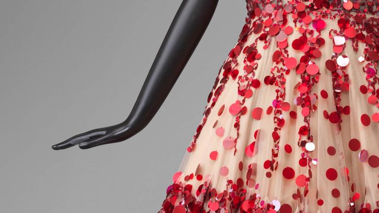 Close-up of the skirt of a white dress with red polka dotsvon a mannequin.