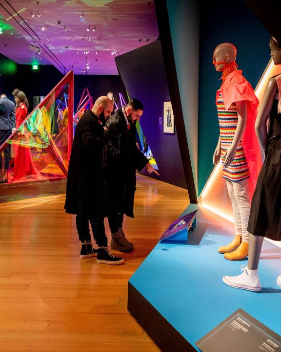 Two people looking at art in Gender Bending Fashion exhibition