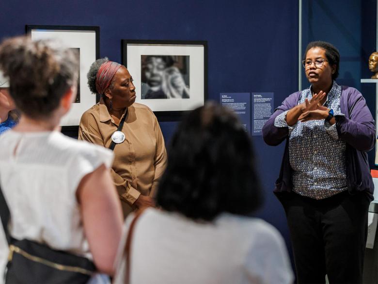 Deaf Interpreter Taki signs about a piece of work in the Art and Jazz gallery.
