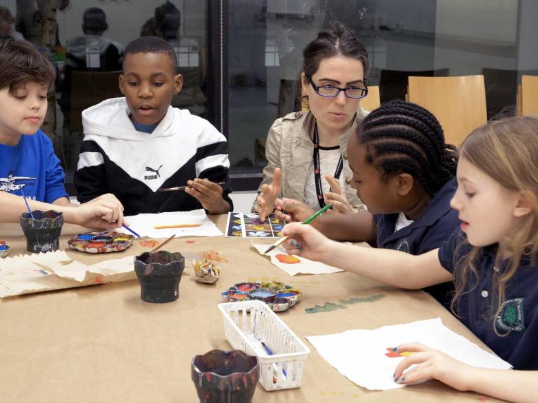 instructor sitting at table with kids working on art project