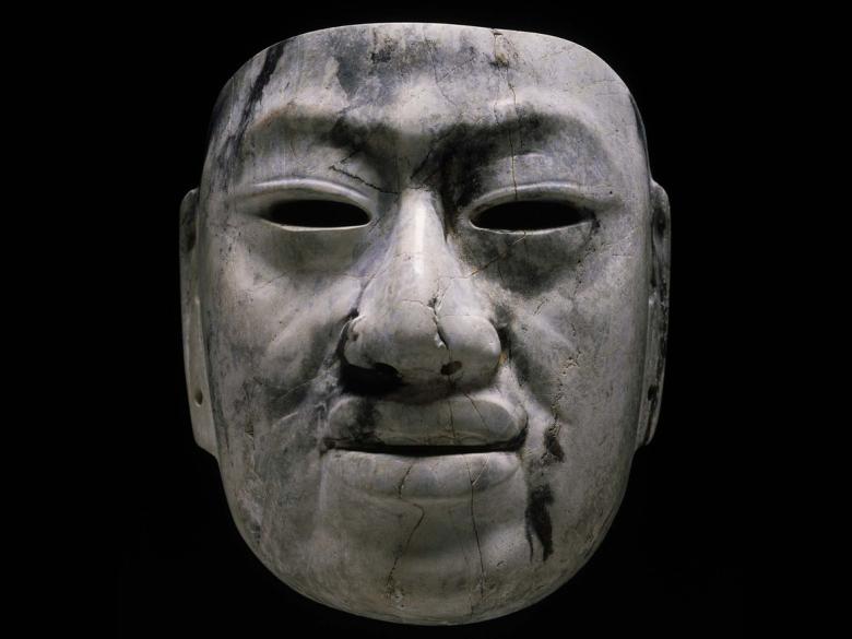 A solemn face carved out of gray and black jadeite.