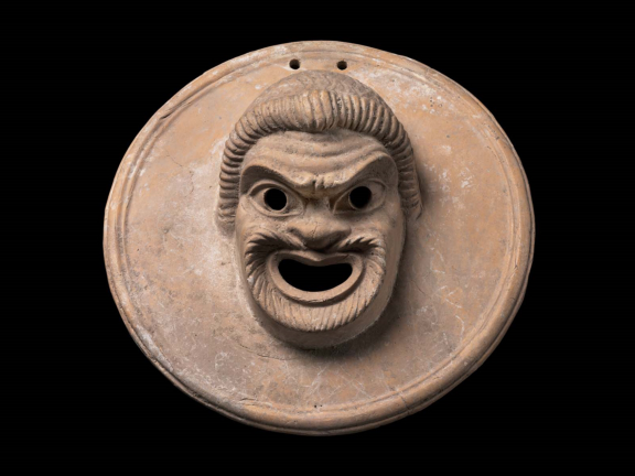 Greek Terracotta suspension disk with an image of a comic mask of a slave