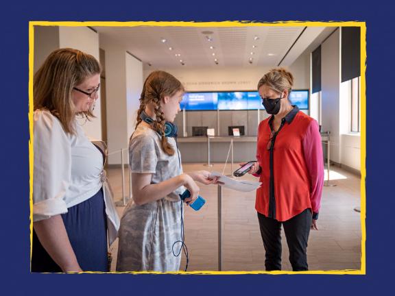 Museum staff person scanning tickets for two visitors