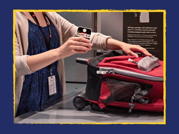 Close-up of bag being handed over to Museum staff person at coat check counter