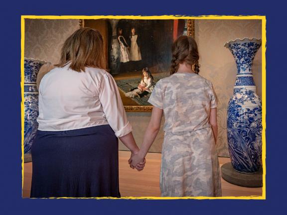 Two visitors holding hands looking at a painting depicting sisters in white dresses