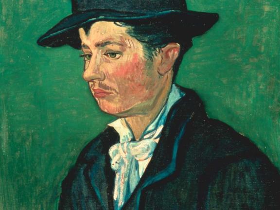 Profile of a man in a yellow jacket, black waistcoat, a tie and a black fedora hat.