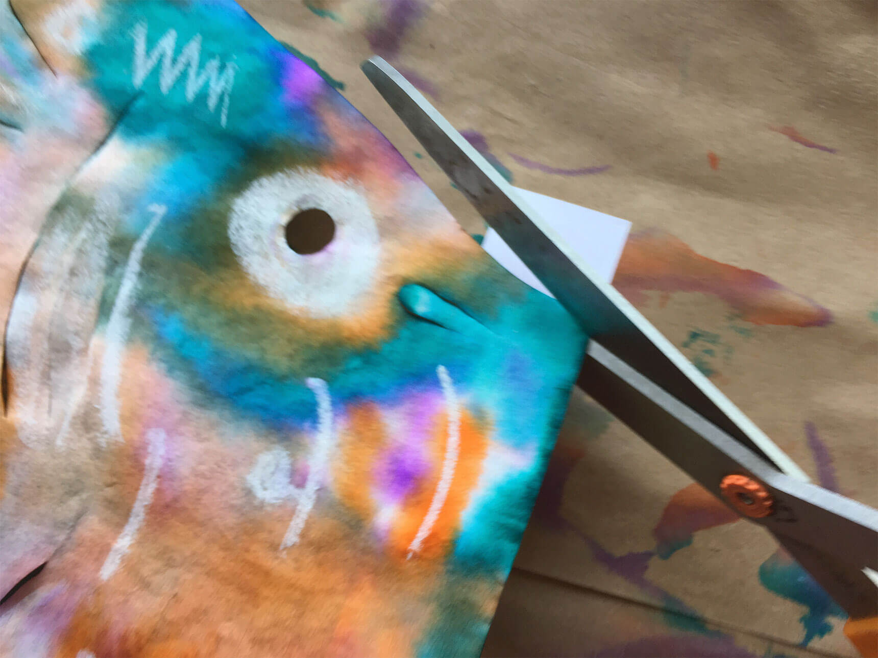 Using scissors to trim the cardstock to fit the mouth of the fish template