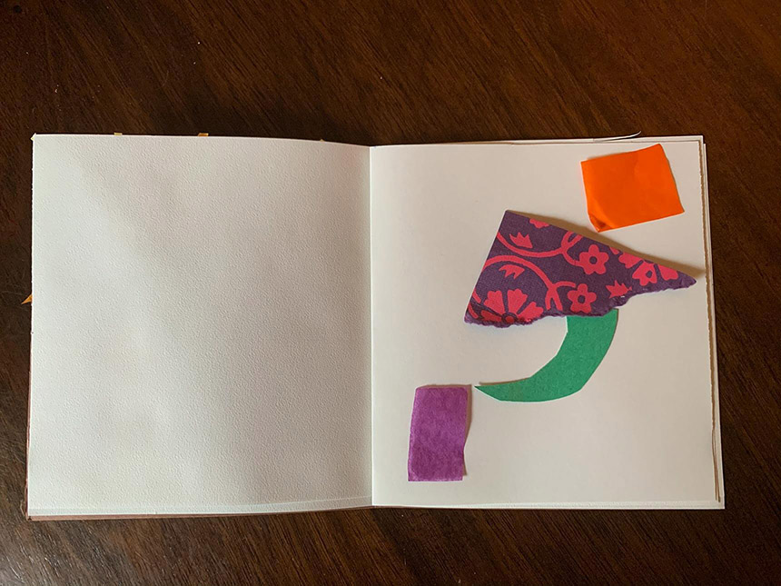 Various bits of cut paper laid out on blank page in sketchbook