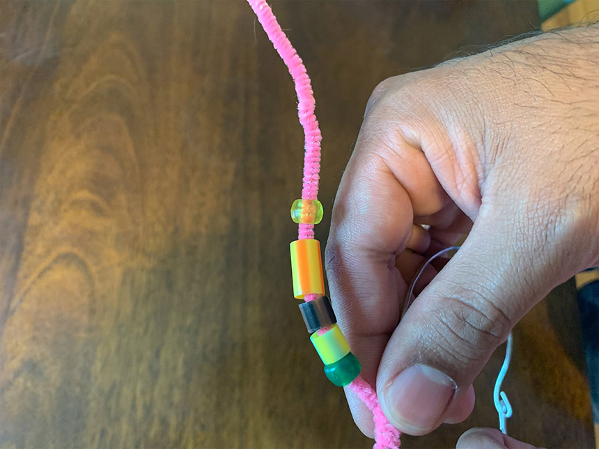 stringing beads of different color through pipe cleaner
