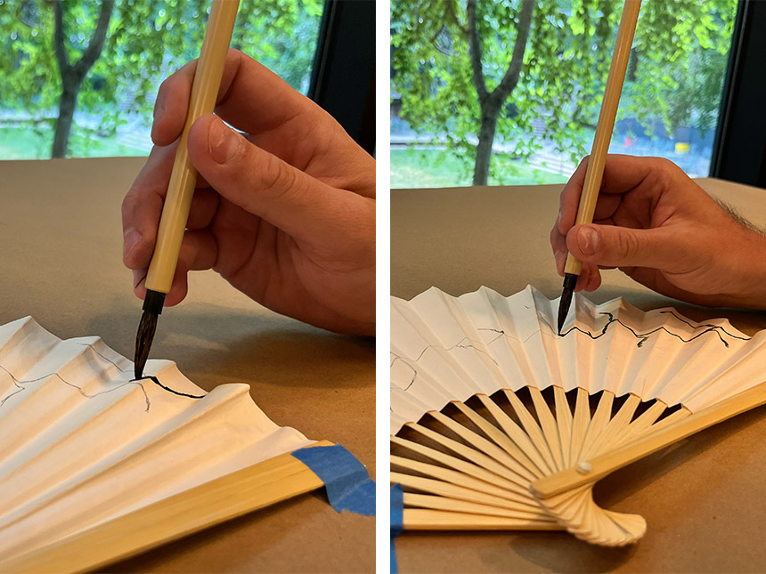 Using paintbrush to paint over lines drawn on fan with pencil