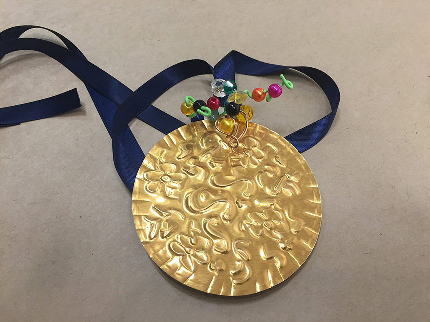 pendant made from embossed gold foil with ribbon for neck strap