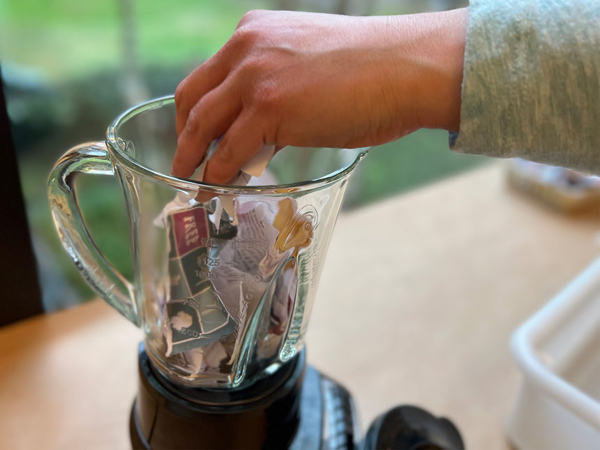 putting pieces of torn paper into blender