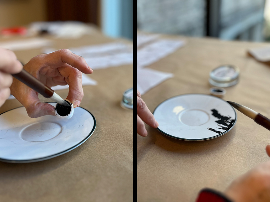 Inserting moistened brush tip into ink block and applying ink onto white ceramic plate with the brush