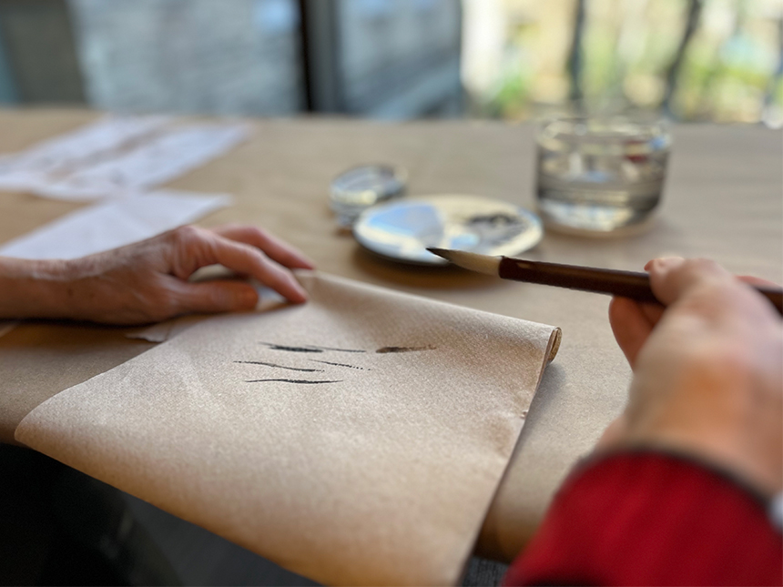 dragging tip of ink brush along paper towel to make sure tip is pointed