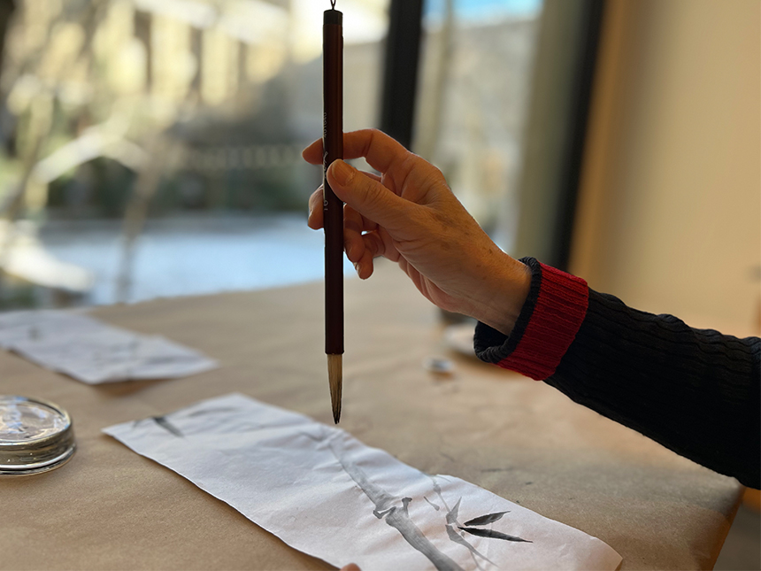 holding ink brush above paper, vertically straight