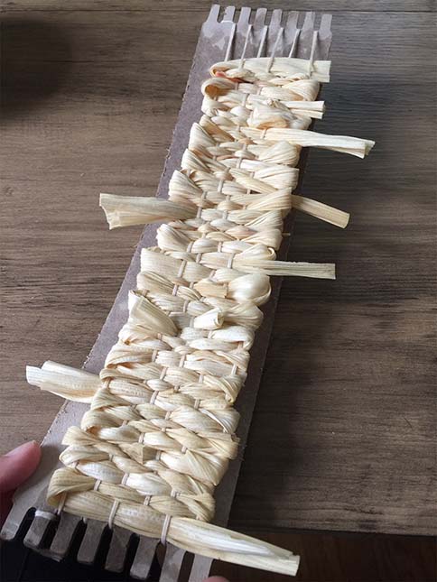 Continuing to weave with corn husk to the top of loom
