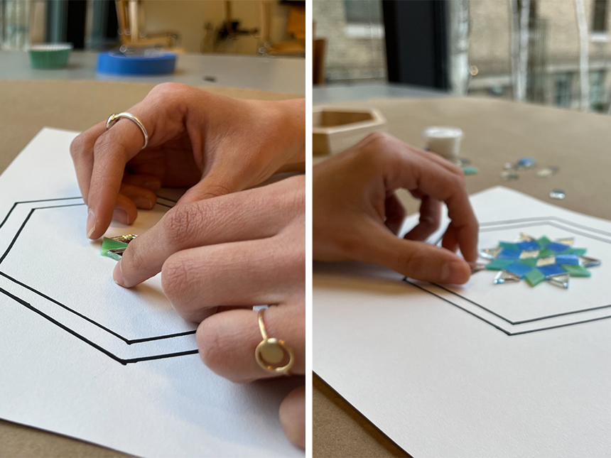 Planning out mosaic pattern by placing and arranging tiles on piece of paper