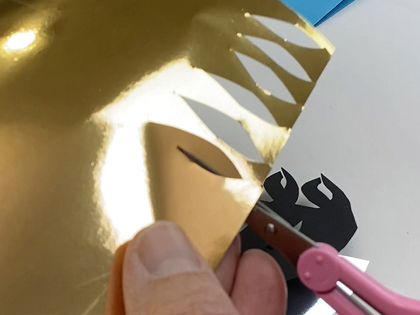 using scissors to cut small flame-shaped pieces from the gold paper