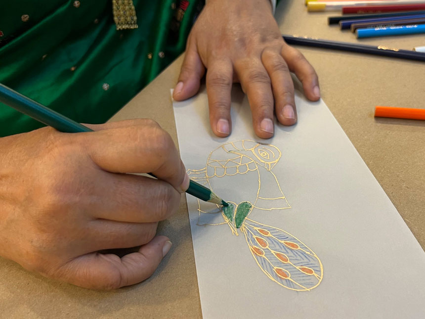 using colored pencils to color in drawing of peacock