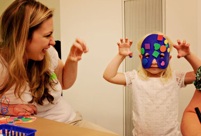 Kid in purple mask making bear claw gestures, with adult looking onwards