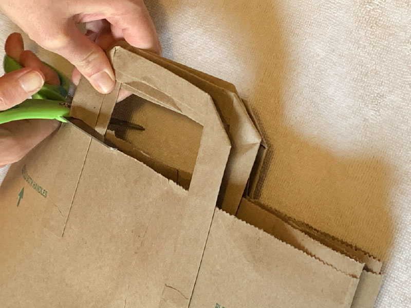 Using scissors to cut off handles from paper grocery bag
