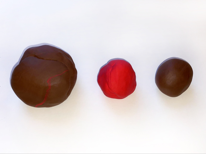 three balls of clay of different colors and sizes