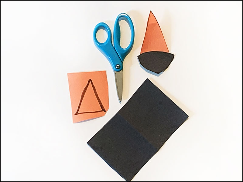 scissors next to pieces of construction paper cut to various shapes