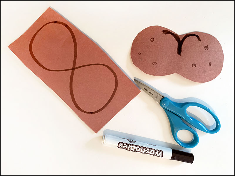 scissors and marker next to brown construction paper with large 8 drawn on it