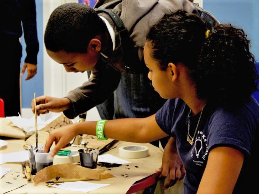 Two teenagers painting with black ink