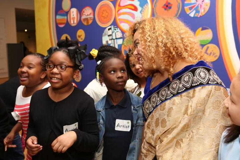 Artist and children talking and looking at artwork