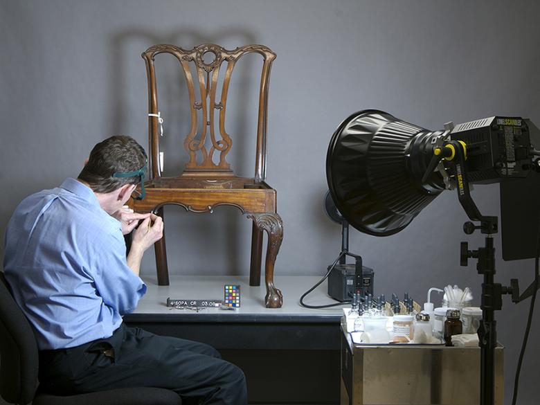 Conservator cleaning the surface of a side chair