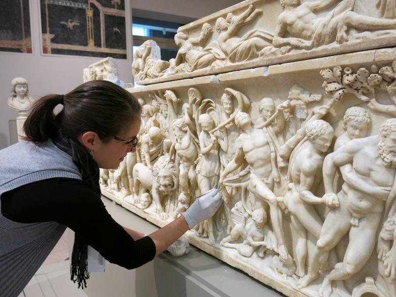 Conservator stabilizing and cleaning a Roman marble sarcophagus