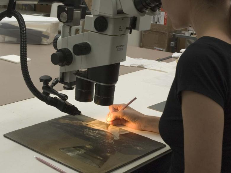 Conservator taking a sample under microscope