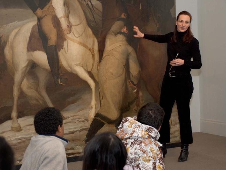 Conservator interacting with students in front of a painting