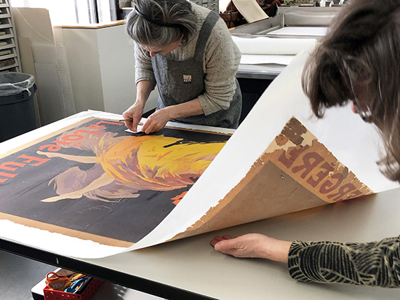 Conservators inspect new lining on Chéret poster