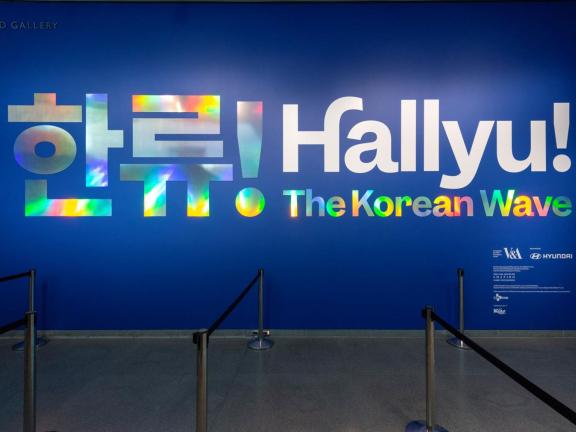 "Hallyu! The Korean Wave" in large metallic letters and Korean characters on wall at exhibition entrance