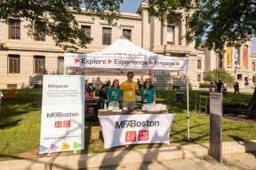 Museum staff standing under tent set up for art making activity outside Museum