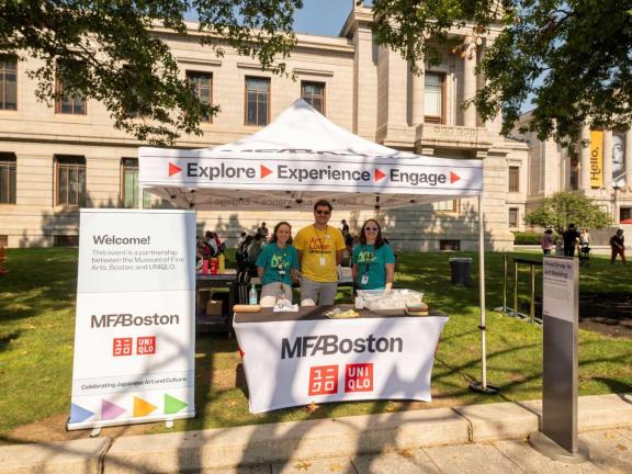 Museum staff standing under tent set up for art making activity outside Museum