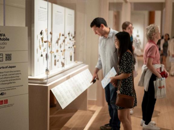 Visitors in Art of Japan gallery looking at various netsuke displayed in tall glass case