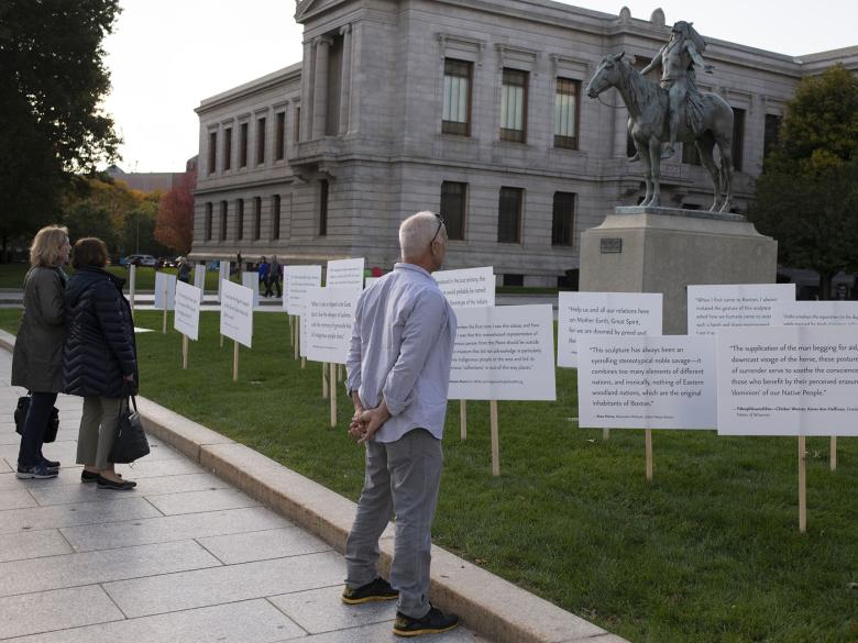 Visitors read signs with written responses to Cyrus Dallin's 'Appeal to the Great Spirit' that surround the sculpture, which depicts a Native American man on horseback.