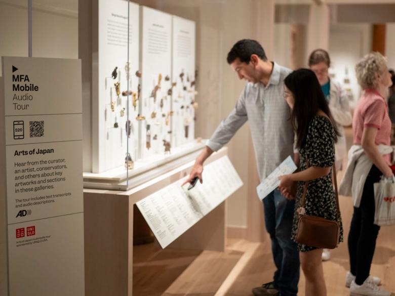 Visitors looking and pointing at display case of netsuke in Art of Japan gallery