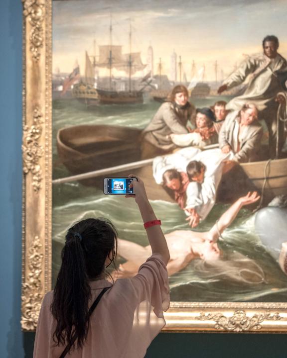 Young visitor holding up smartphone to take photograph of Copley's Watson and the Shark painting