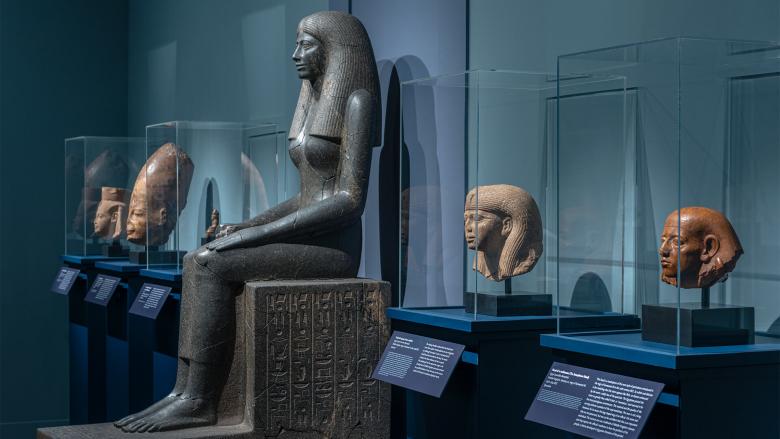 Various Egyptian sculptures lined up on cases in gallery