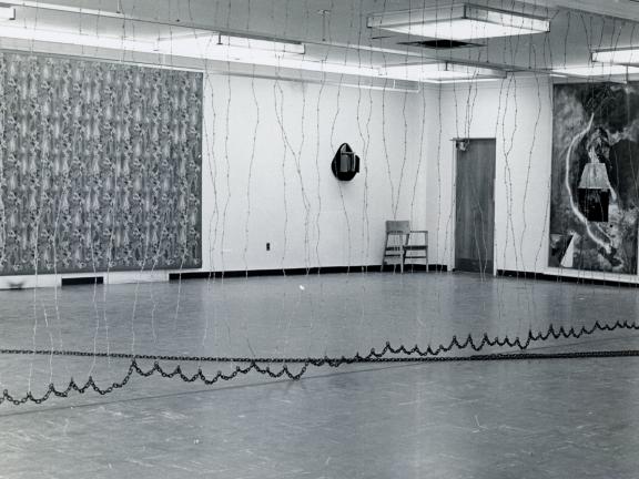 The "5+1" gallery space is split by a barbed wire curtain.