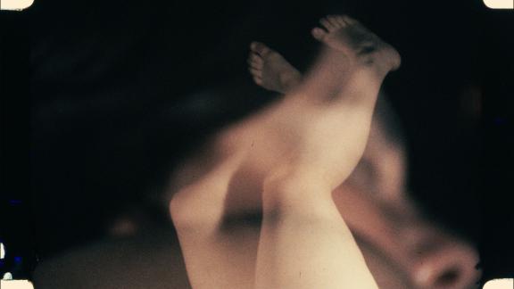 A blurred image of feet and legs against a black background.