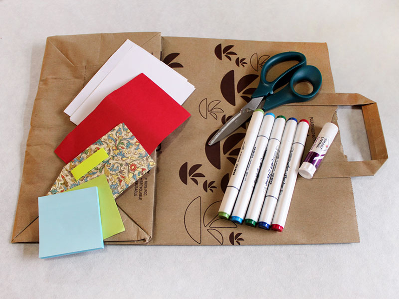 various art supplies laid out on top of paper grocery bag