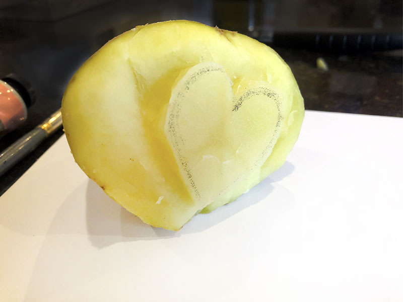 potato half with parts carved off around drawn heart
