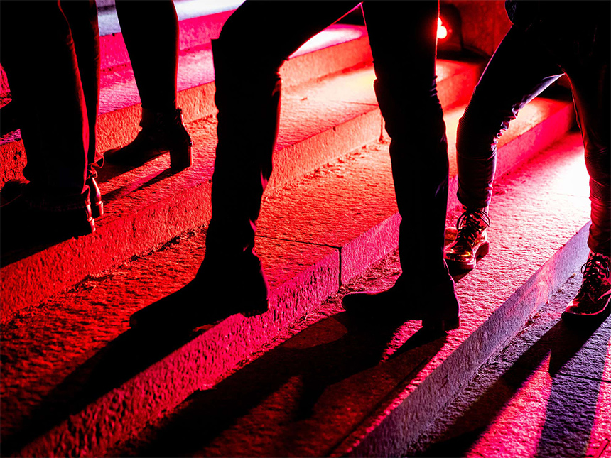 Silhouette of legs walking outside Museum, cast in bright red light