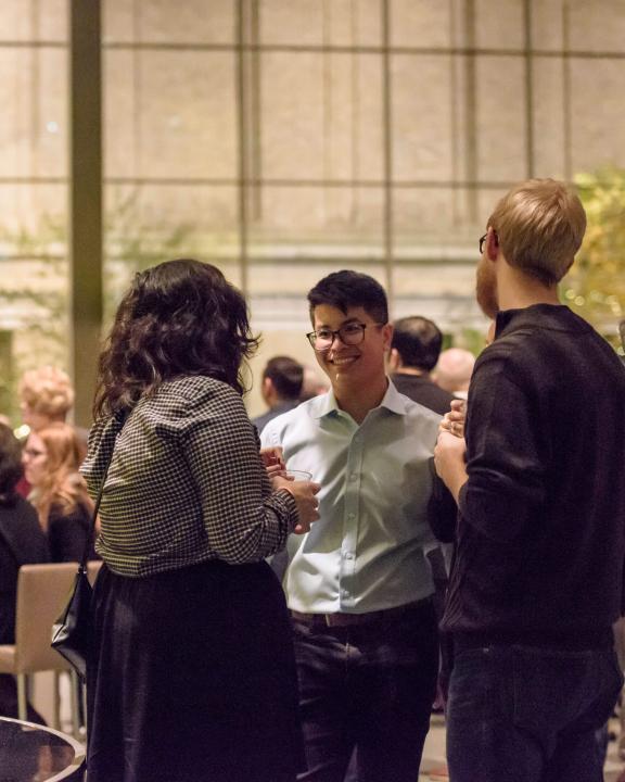 Visitors mingling near Lime Green Icicle Tower in Shapiro Family Courtyard with drinks in hand